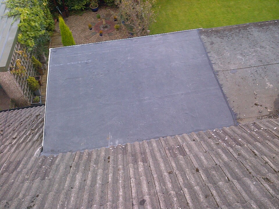 EPDM dakbedekking op een platte aanbouw, omgeven door een hellend pannendak